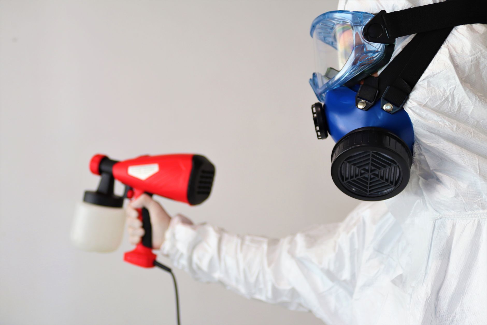 IICRC-certified mold remediation technician in full PPE inspecting a wall with a moisture meter in a Burleson home, with containment barriers visible in the background.