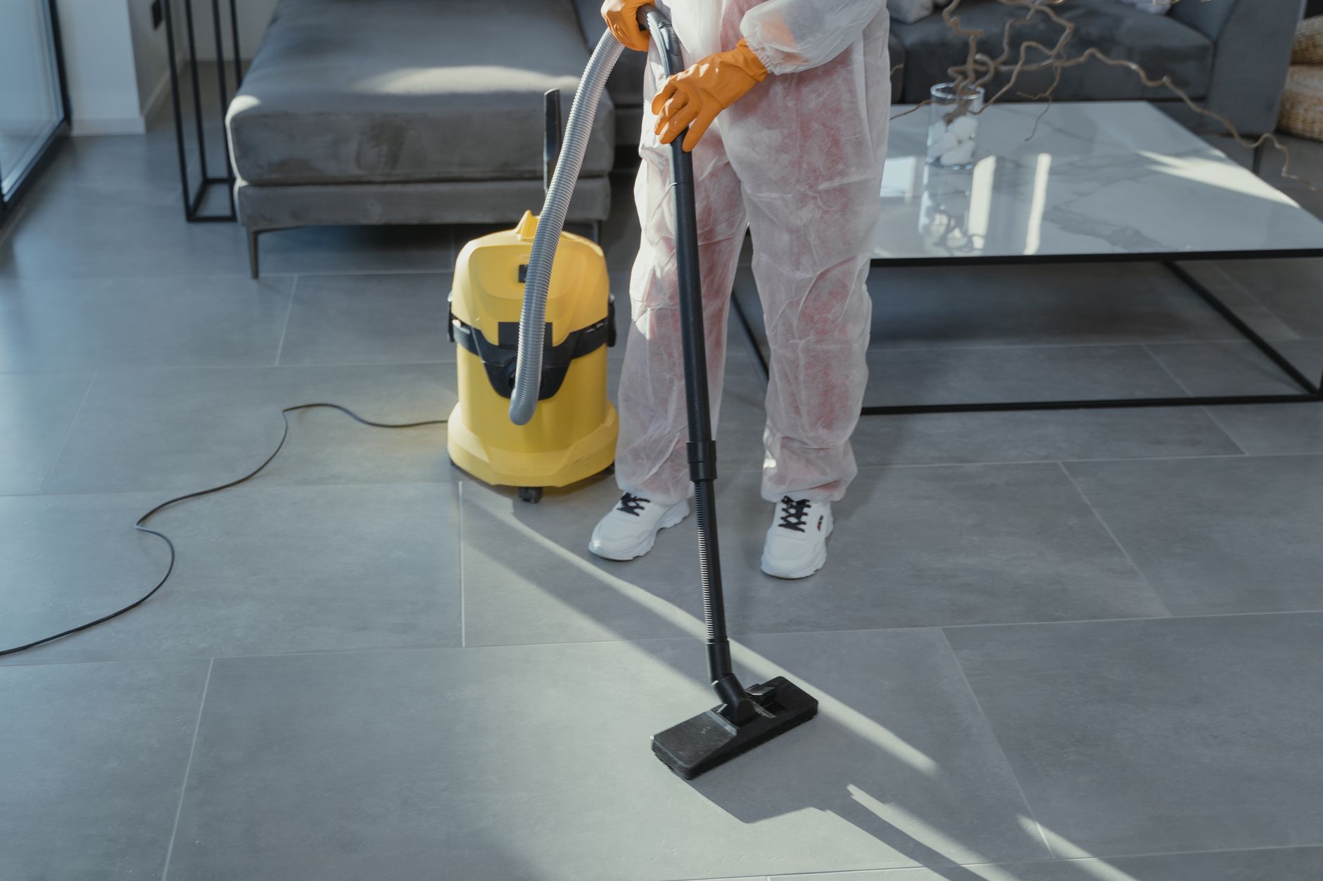 Close-up of a mold remediation technician in Burleson, Texas, wearing a respirator and protective gear, carefully removing mold-affected drywall from a residential interior.